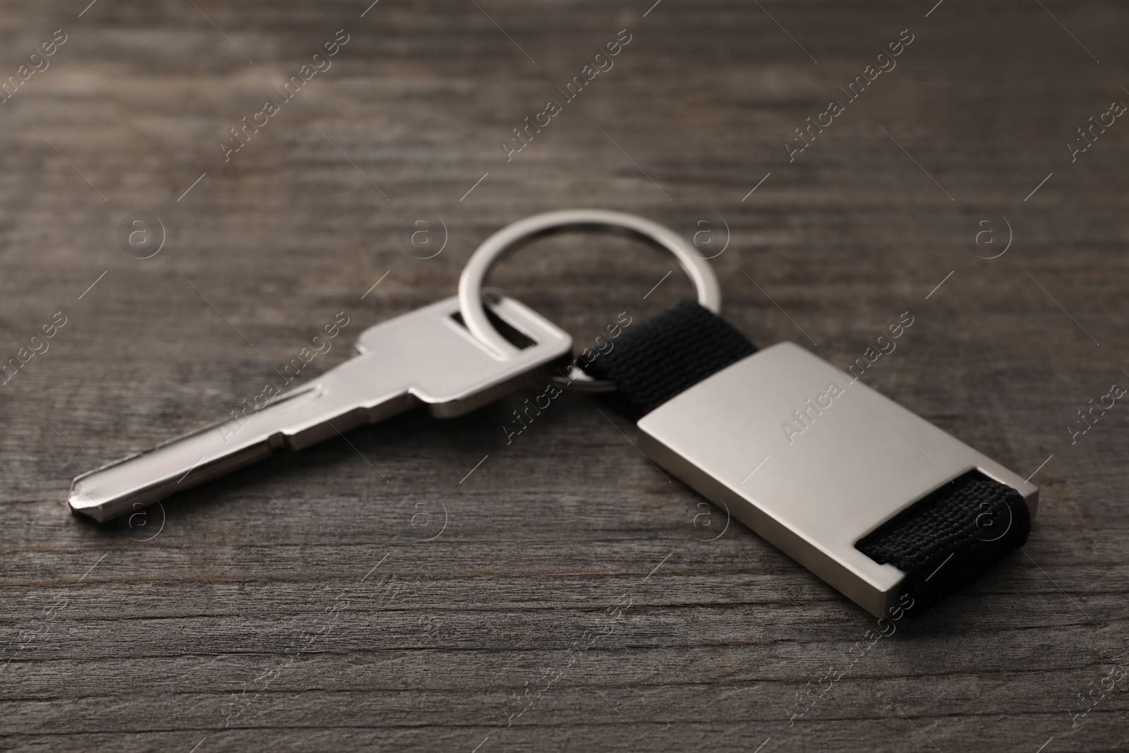 Photo of Key with metallic keychain on wooden background, closeup
