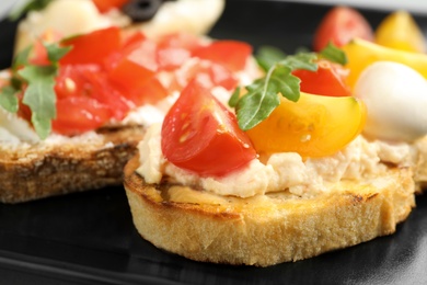 Delicious tomato bruschetta on black plate, closeup