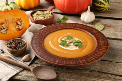 Photo of Delicious pumpkin soup with seeds and parsley served on wooden table