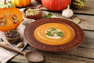 Delicious pumpkin soup with seeds and parsley served on wooden table