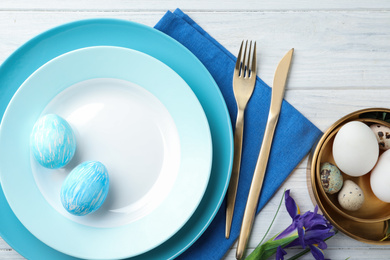 Festive Easter table setting with eggs on wooden background, flat lay