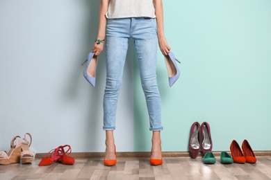 Photo of Young woman with different shoes near color wall, closeup