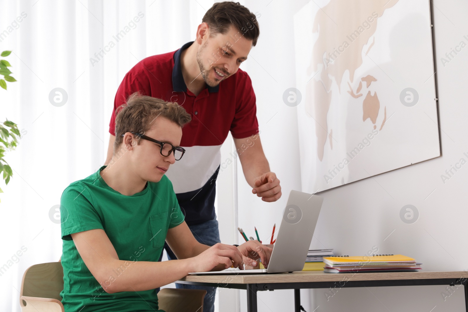 Photo of Father helping his teenager son with homework indoors