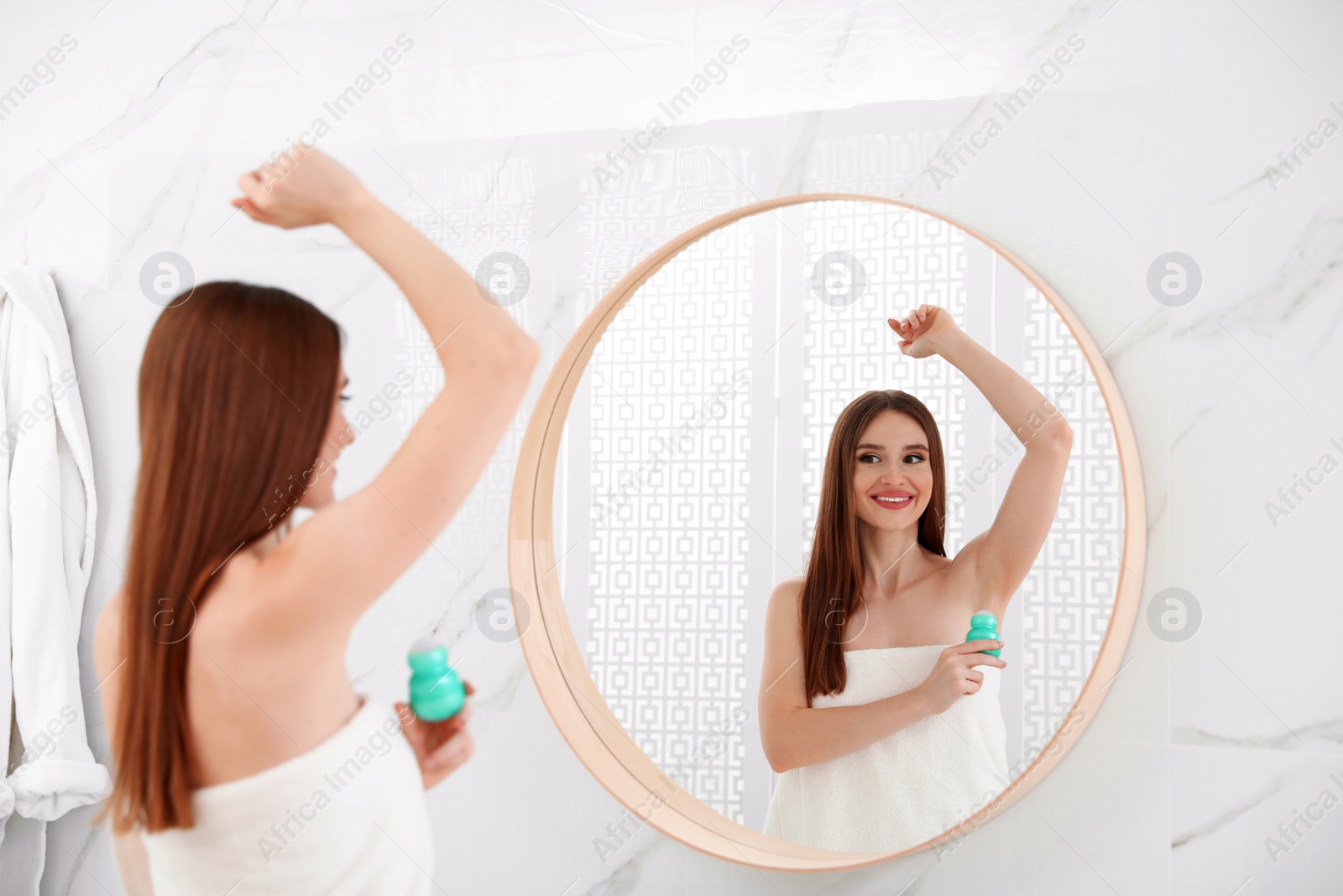 Photo of Beautiful young woman applying deodorant after shower in bathroom