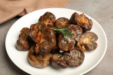 Photo of Plate with delicious kidneys and rosemary on light table, closeup