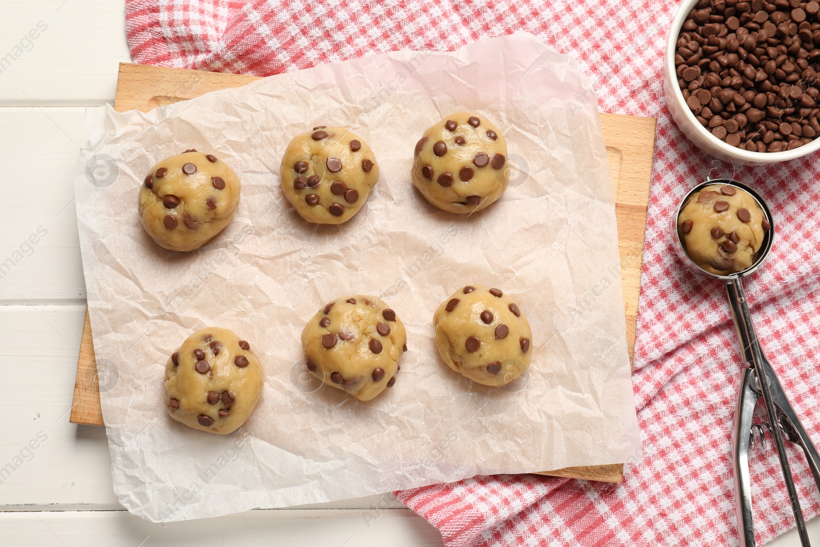 Photo of Uncooked chocolate chip cookies on white wooden table, flat lay