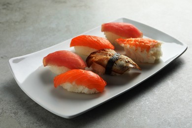 Photo of Plate with delicious nigiri sushi on grey table