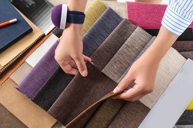 Photo of Young woman choosing among upholstery fabric samples, closeup. Interior design