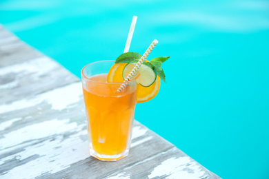 Photo of Refreshing cocktail near outdoor swimming pool on sunny day