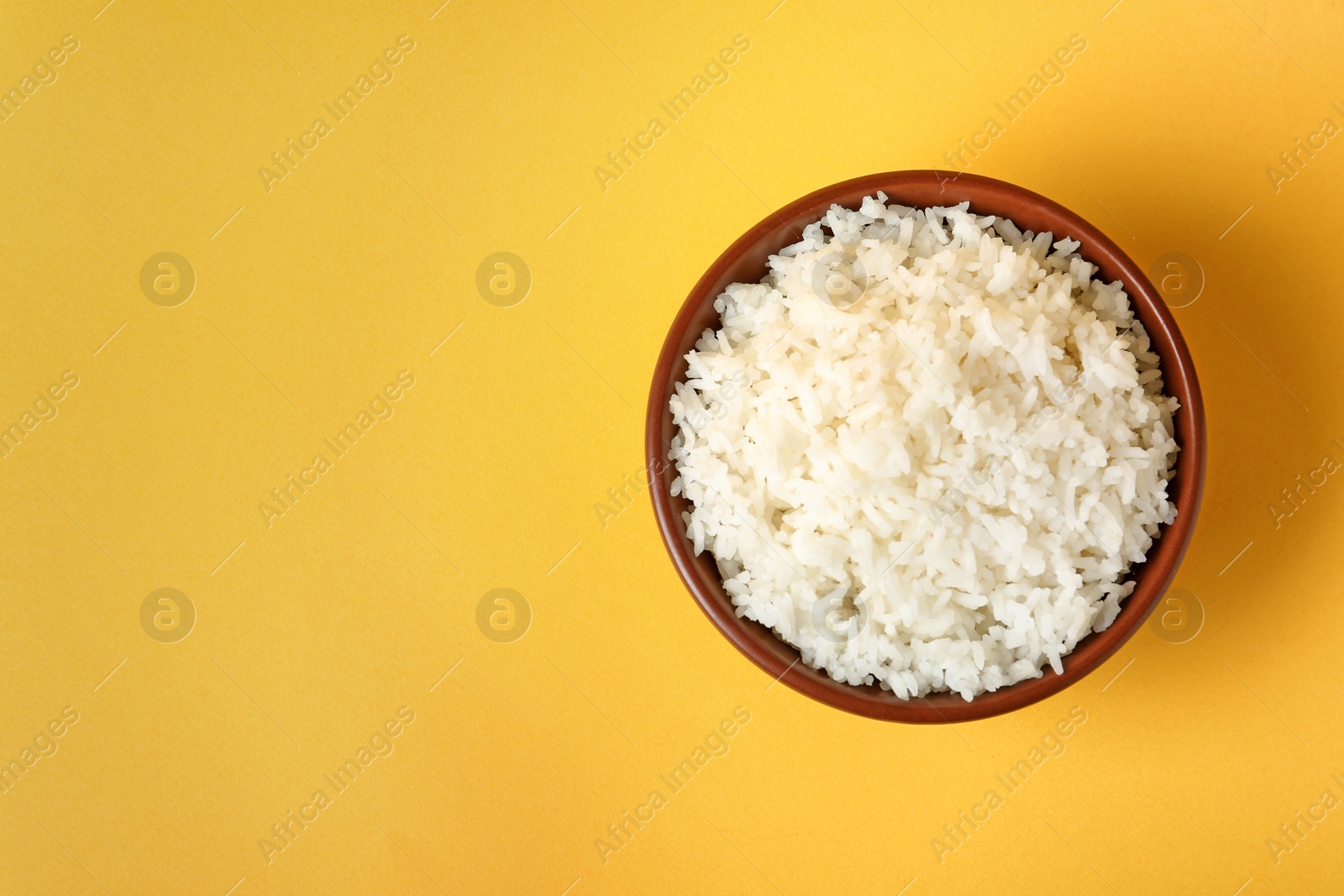 Photo of Bowl of boiled rice on color background, top view with space for text