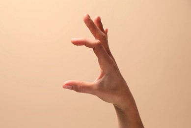 Photo of Woman holding something in hand on beige background, closeup. Space for text