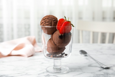Photo of Glass bowl of chocolate ice cream with strawberry on marble table