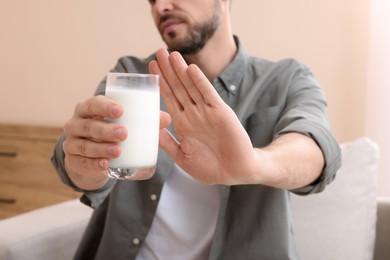 Photo of Man with glass of milk suffering from lactose intolerance at home, closeup