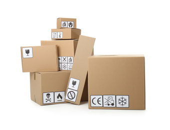 Photo of Cardboard boxes with different packaging symbols on white background. Parcel delivery