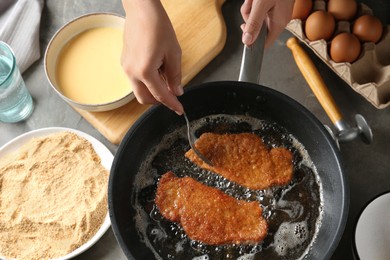 Photo of Woman cooking schnitzels in frying pan, top view