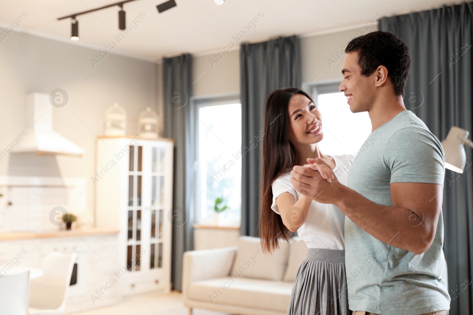 Photo of Lovely young interracial couple dancing at home. Space for text