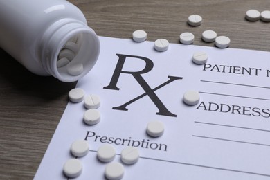 Medical prescription form, pills and bottle on wooden table, closeup
