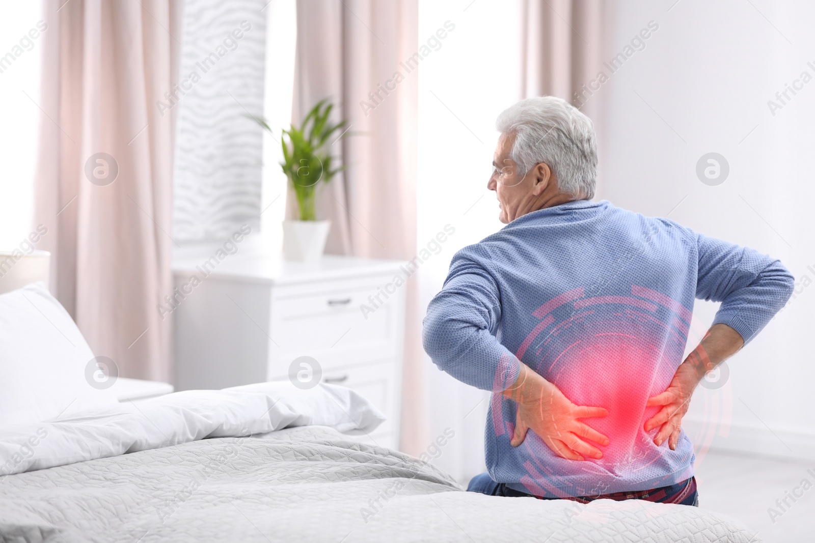 Image of Senior man suffering from back pain after sleeping on uncomfortable mattress at home