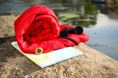 Rolled sleeping bag and other camping gear outdoors on sunny day