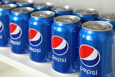 Photo of MYKOLAIV, UKRAINE - FEBRUARY 10, 2021: Cans of Pepsi on white shelf, closeup