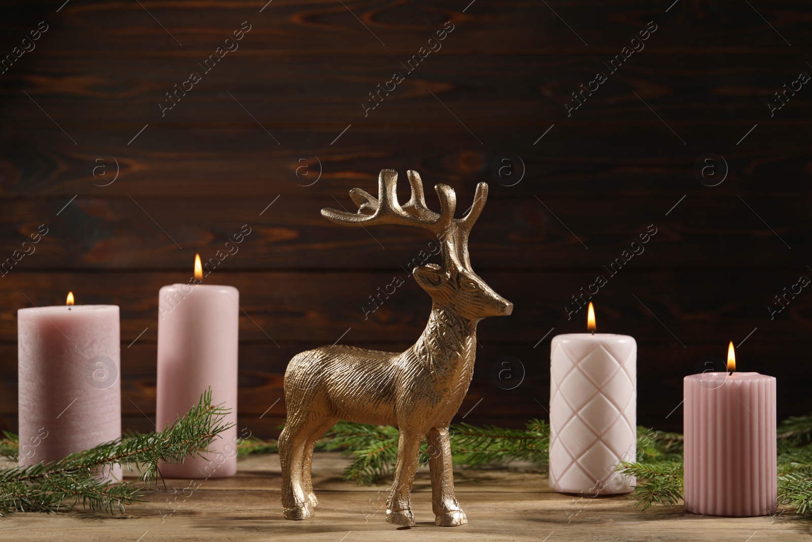 Photo of Beautiful deer figure and burning candles on wooden table