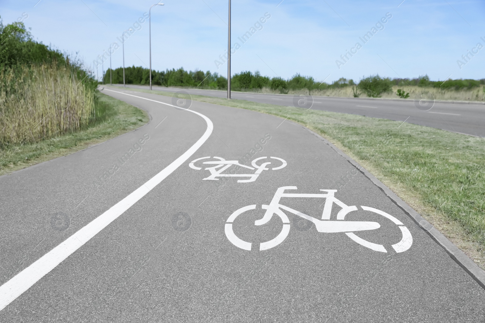 Photo of Bicycle lane with white sign painted on asphalt near sidewalk