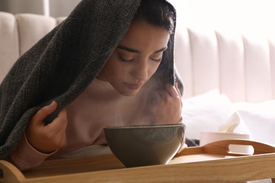 Woman with plaid doing inhalation above bowl indoors