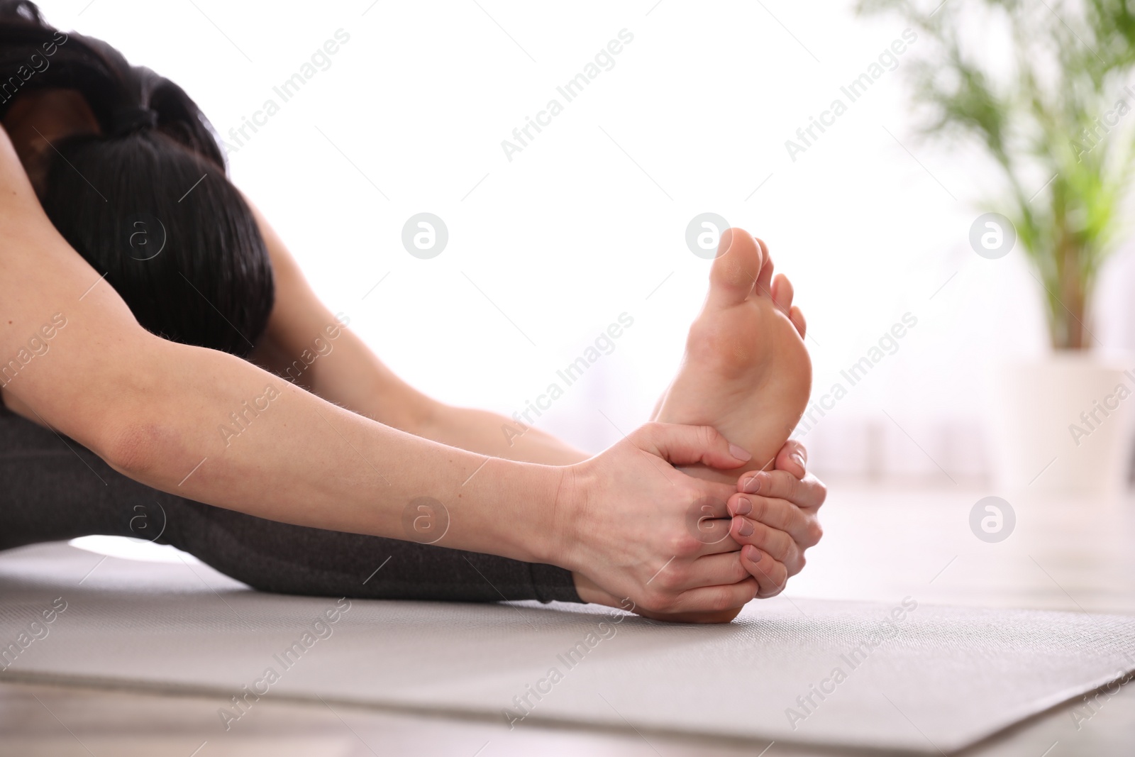 Photo of Young woman practicing head to knee asana in yoga studio, closeup. Janu Sirsasana pose