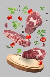 Image of Beef meat, different spices and board falling on grey background