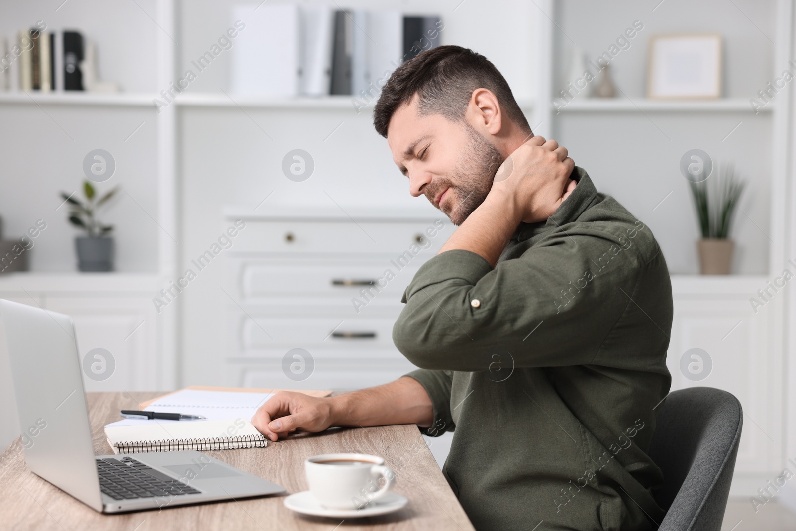 Photo of Man suffering from neck pain in office