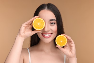 Photo of Beautiful young woman with pieces of orange on beige background