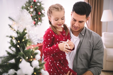 Photo of Father with his cute daughter decorating Christmas tree together at home