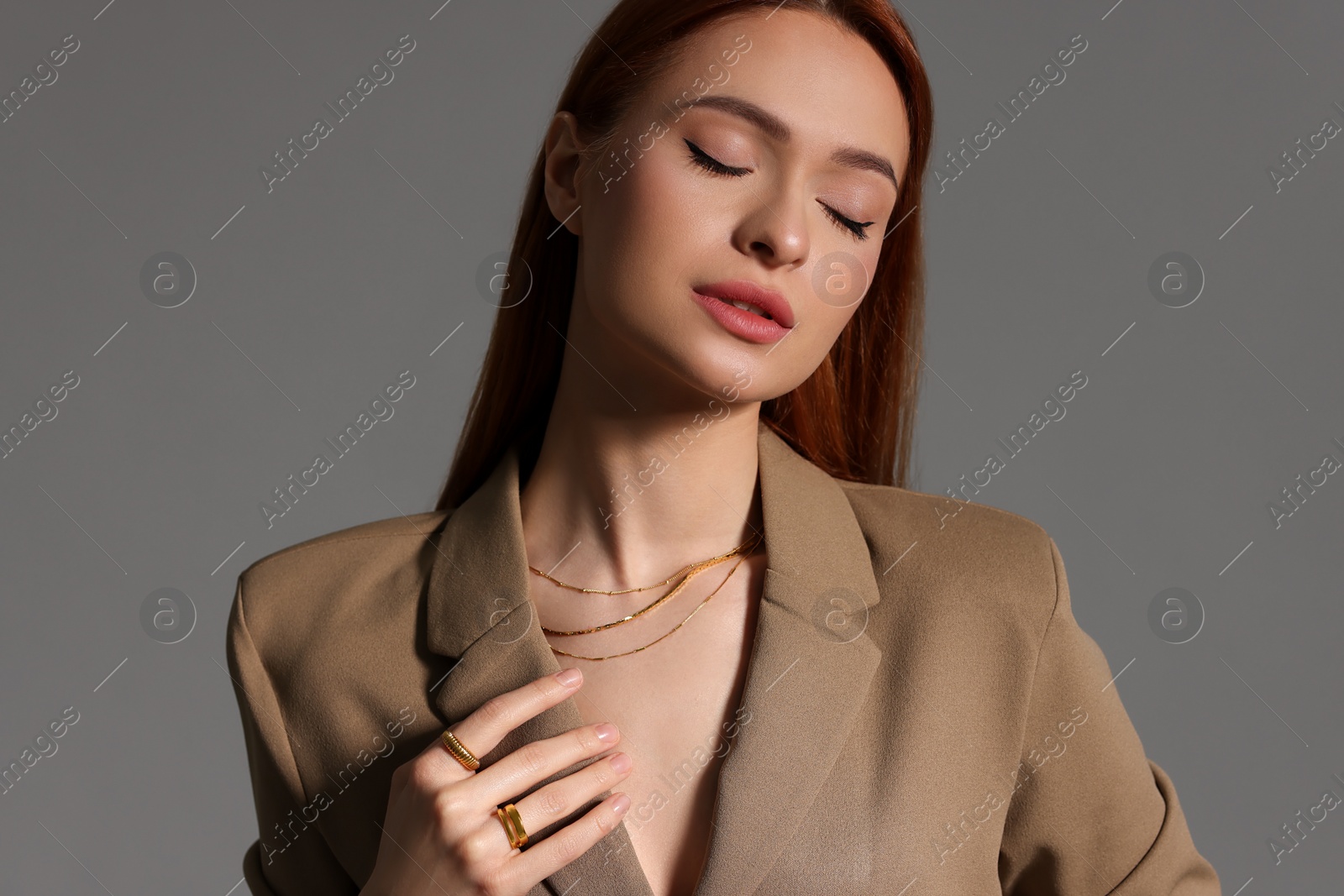 Photo of Beautiful young woman with elegant jewelry on gray background