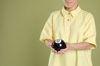 Photo of Man holding magic eight ball on olive background, closeup. Space for text