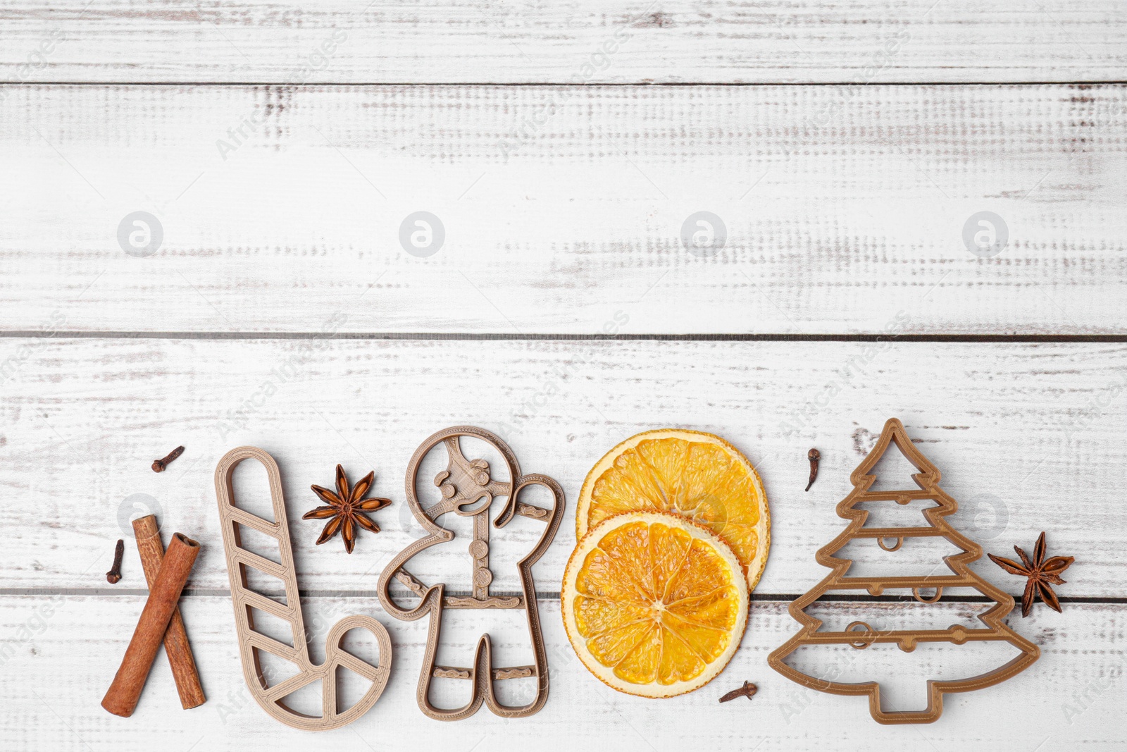 Photo of Christmas treat. Flat lay composition with cookie cutters on white wooden table. Space for text