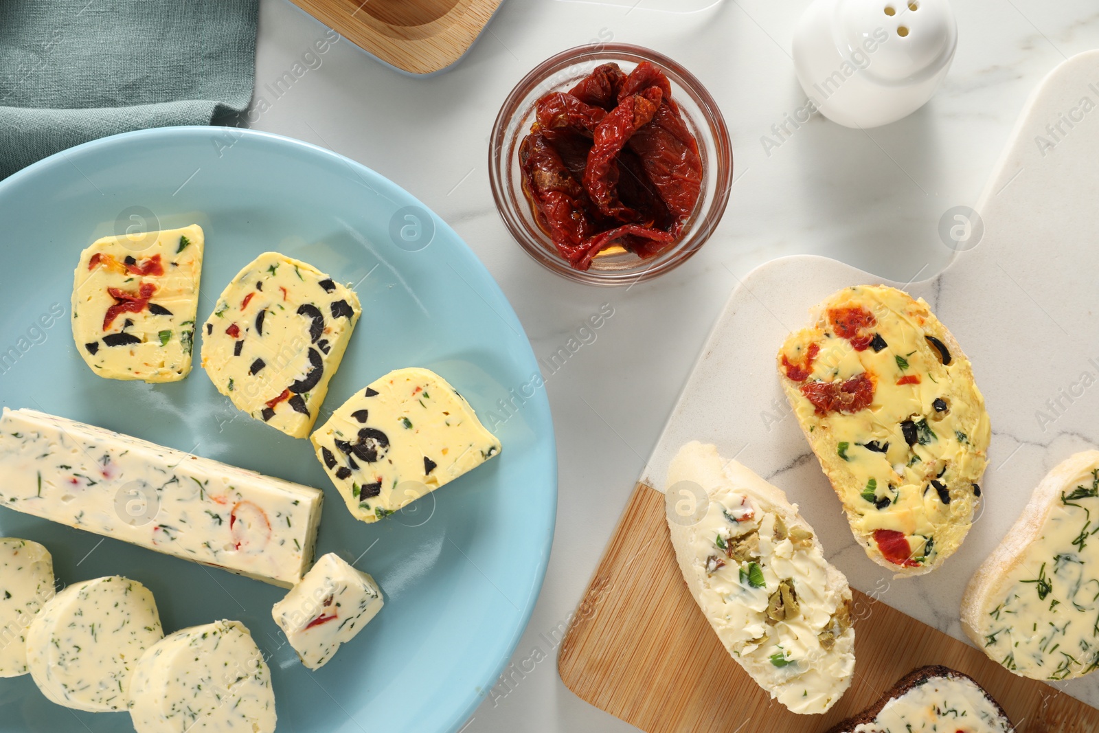 Photo of Different types of tasty butter, bread and chili peppers on white marble table, flat lay