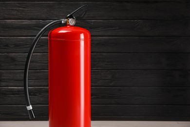 Fire extinguisher against wooden wall. Space for text