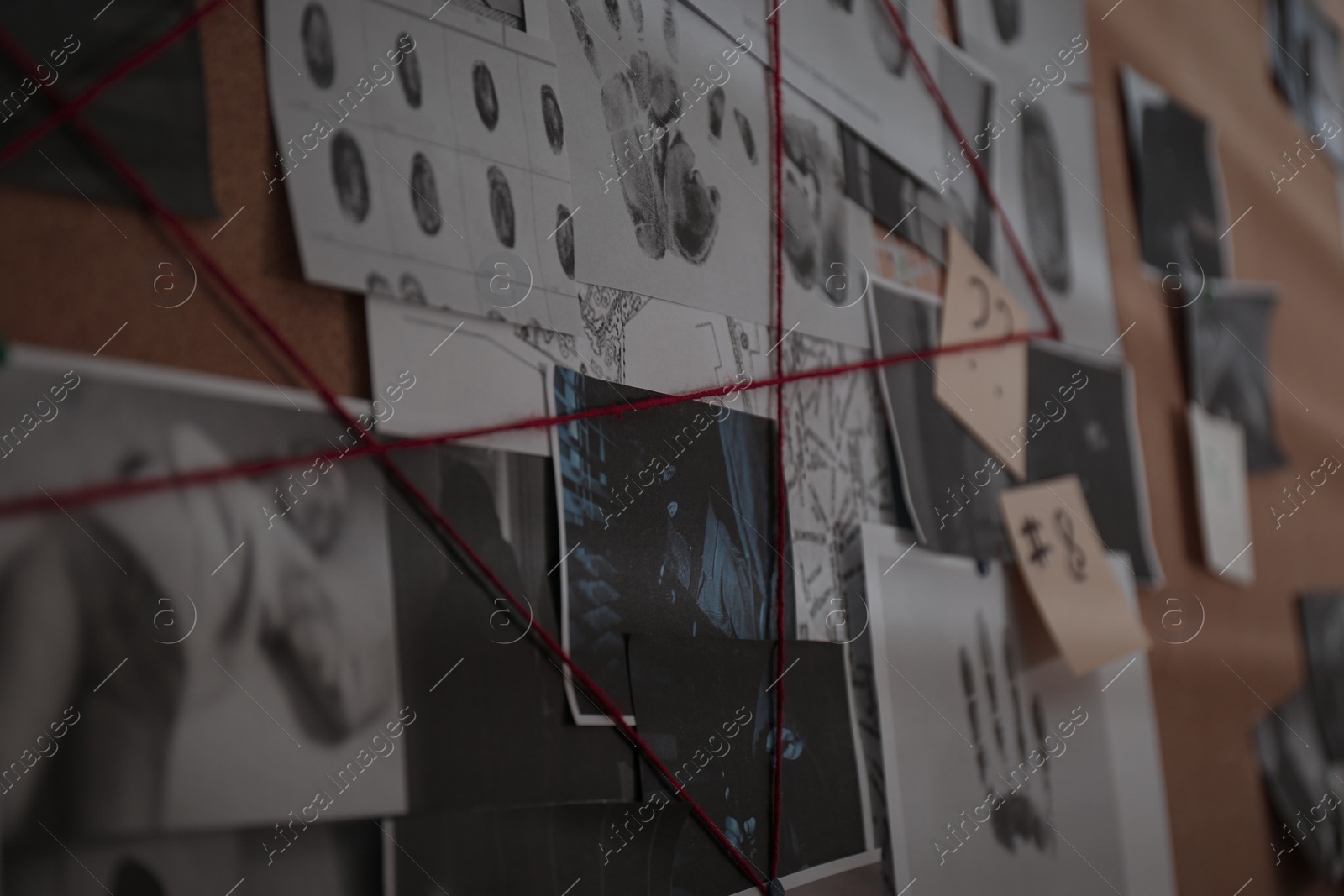 Photo of Detective board with crime scene photos, stickers, clues and red thread, closeup