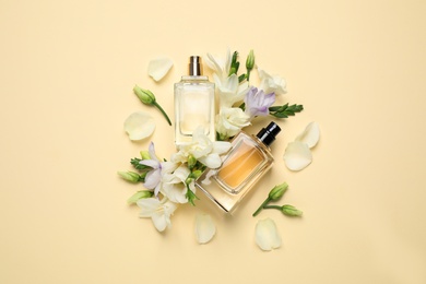 Photo of Flat lay composition with different perfume bottles and freesia flowers on yellow background
