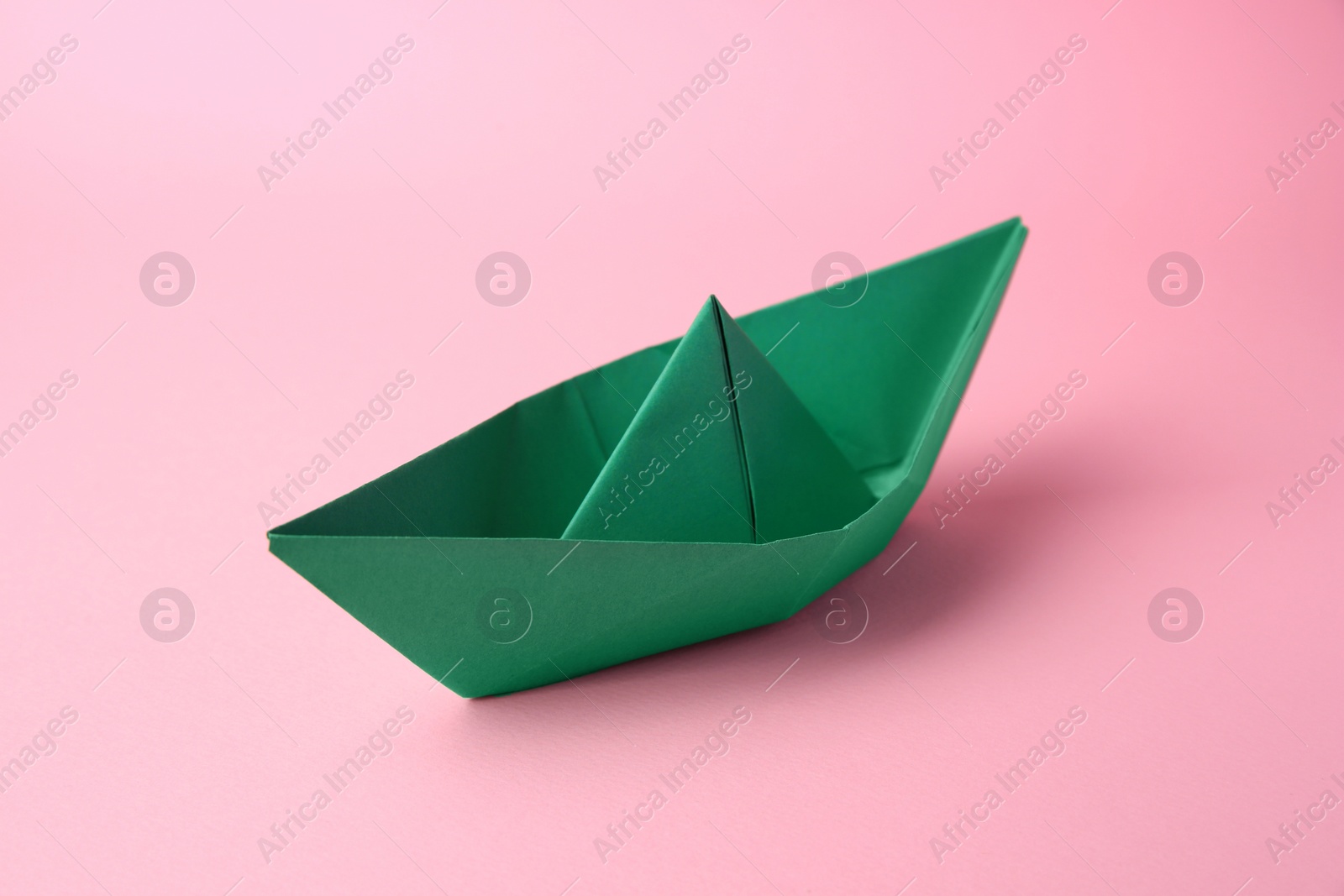 Photo of Origami art. Paper boat on pink background