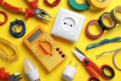 Flat lay composition with electrician's tools and accessories on yellow background