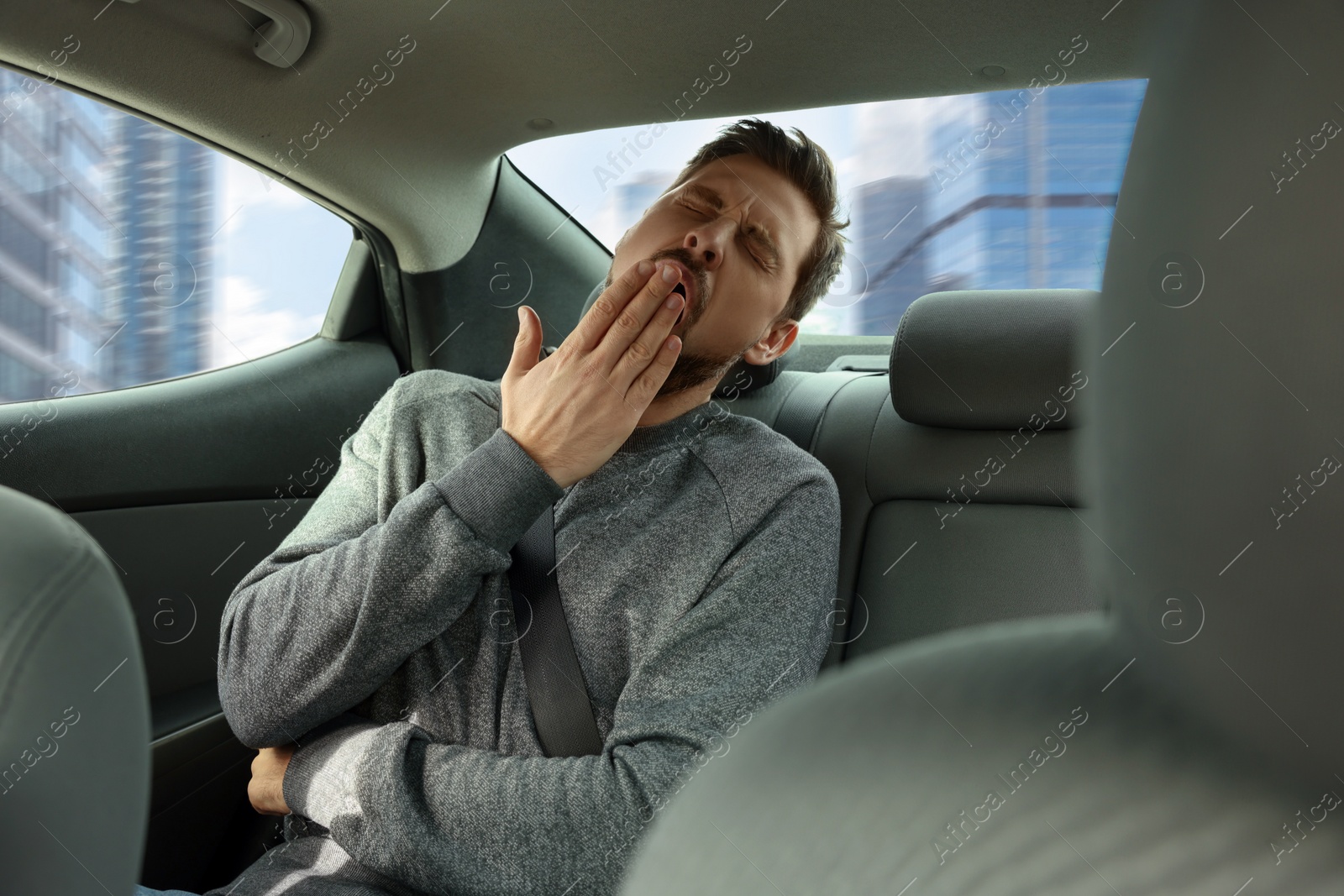 Photo of Sleepy tired man yawning in modern car