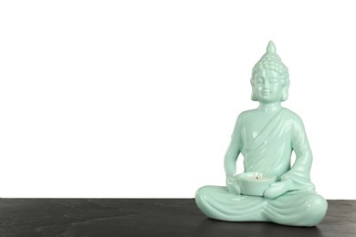 Photo of Beautiful ceramic Buddha sculpture with burning candle on table against grey background. Space for text