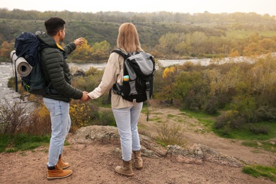 Couple of travelers with backpacks enjoying beautiful view near mountain river. Autumn vacation