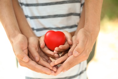 Photo of Adult and child hands holding heart on blurred background, closeup. Family concept