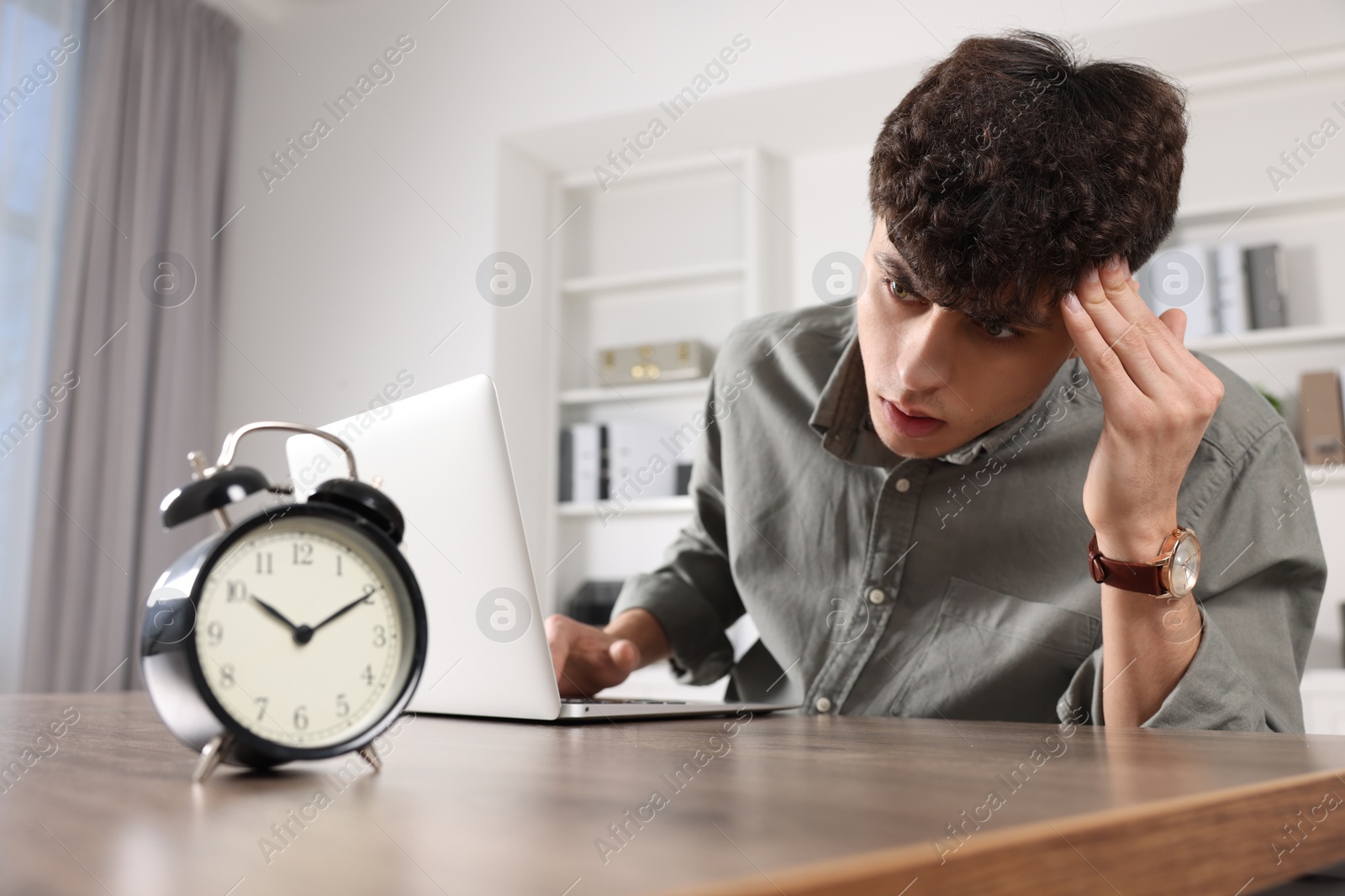 Photo of Emotional young man working at table in office. Deadline concept