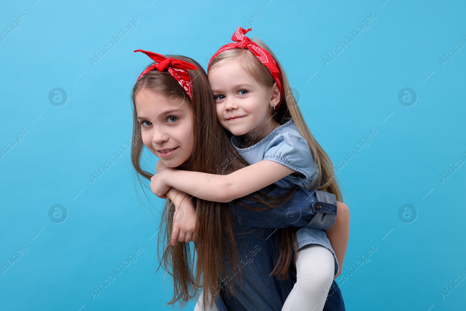 Photo of Cute little sisters on light blue background