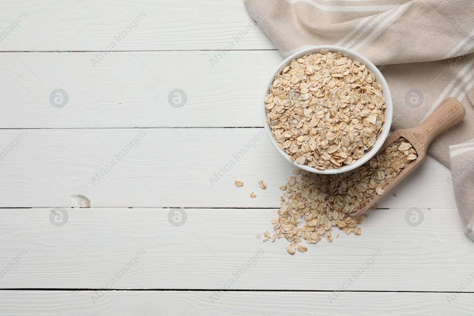 Photo of Bowl and scoop with oatmeal on white wooden table, flat lay. Space for text