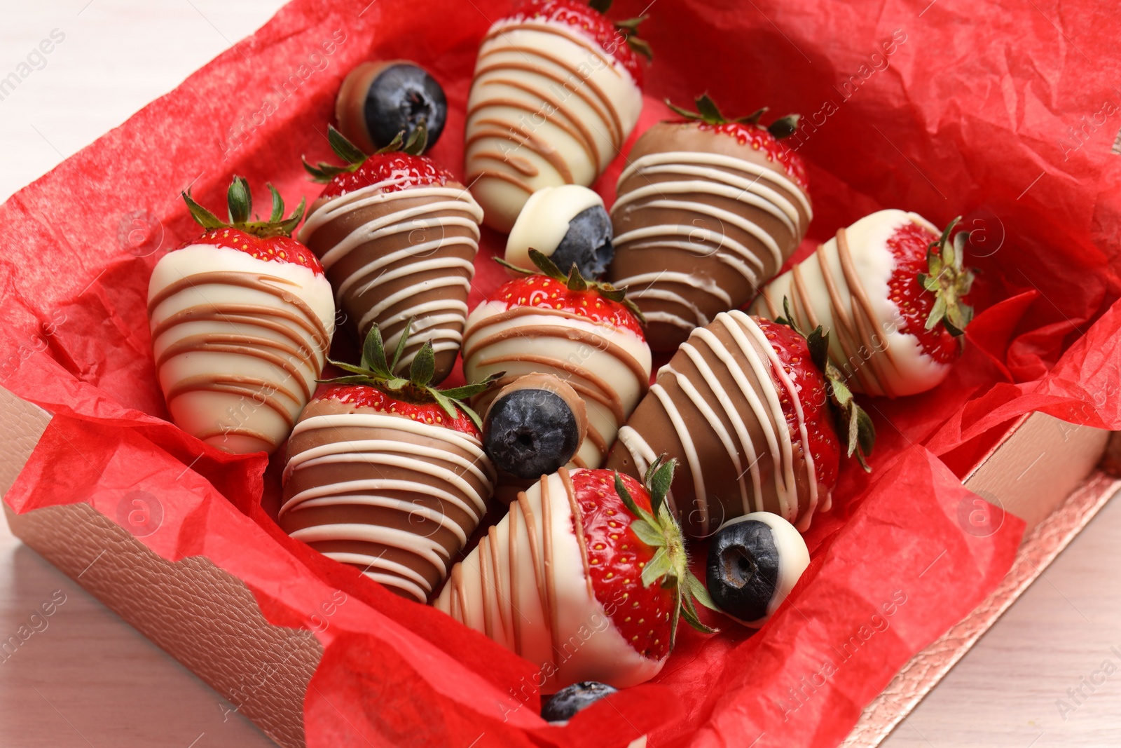 Photo of Box with delicious chocolate covered strawberries and blueberries on white table, closeup