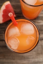 Tasty freshly made grapefruit juice and fruit on wooden table, top view